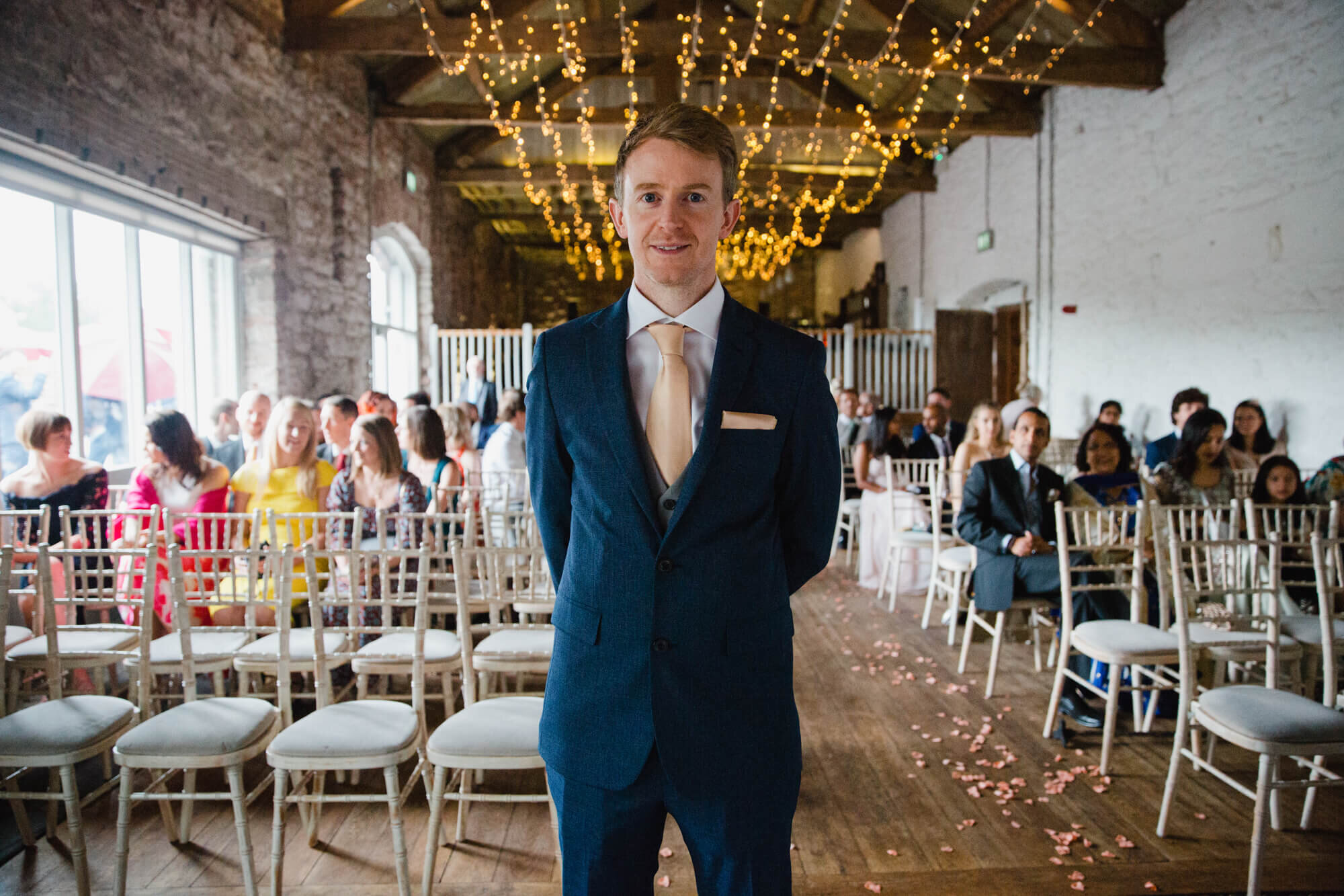 groom at top of aisle on exhibition as guests look on