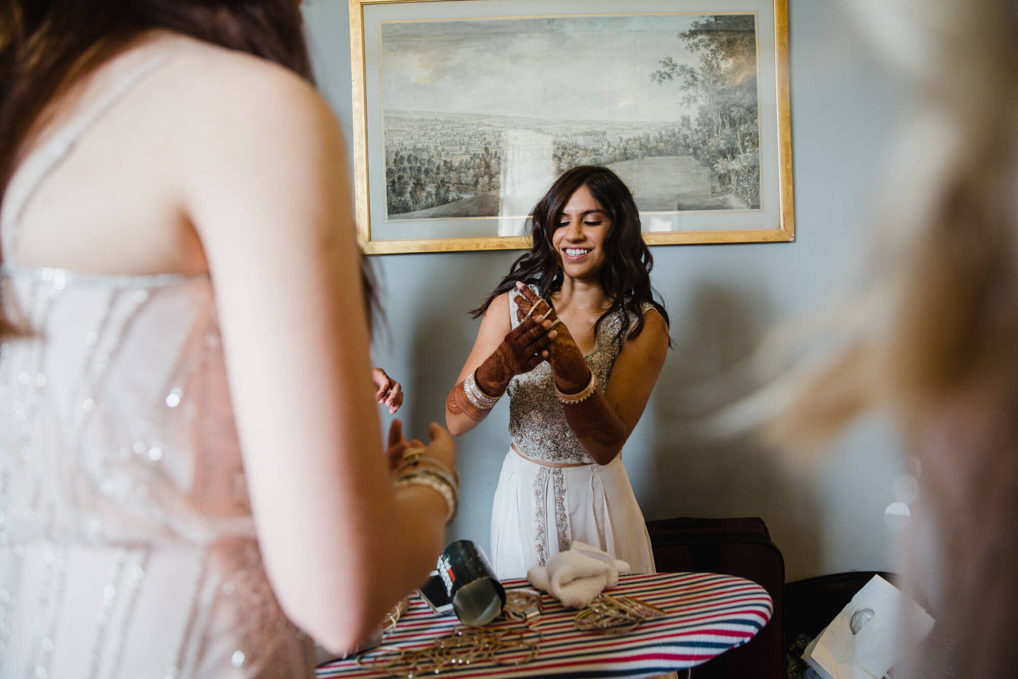 bride surrounded by bridesmaid group as she dresses with bangle kit