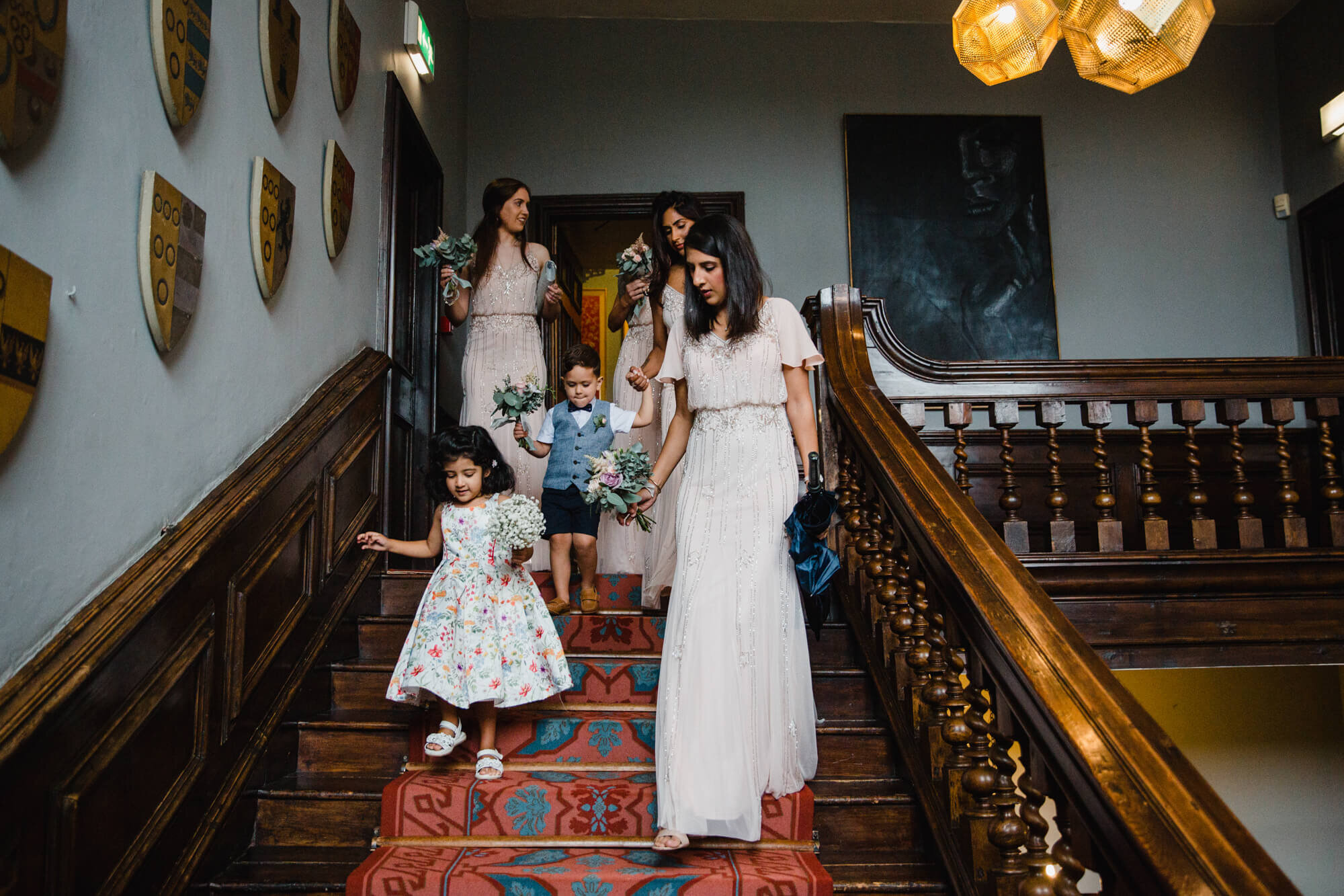 bridesmaids descending staircase carrying gifts for bride