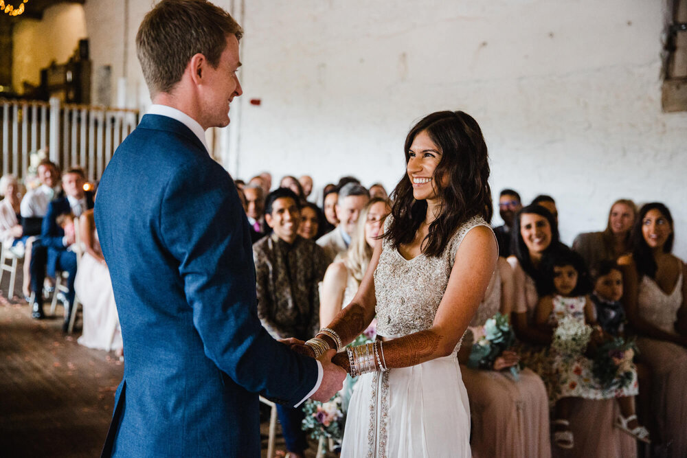 bride smiles at groom as registrar gives tips on marriage