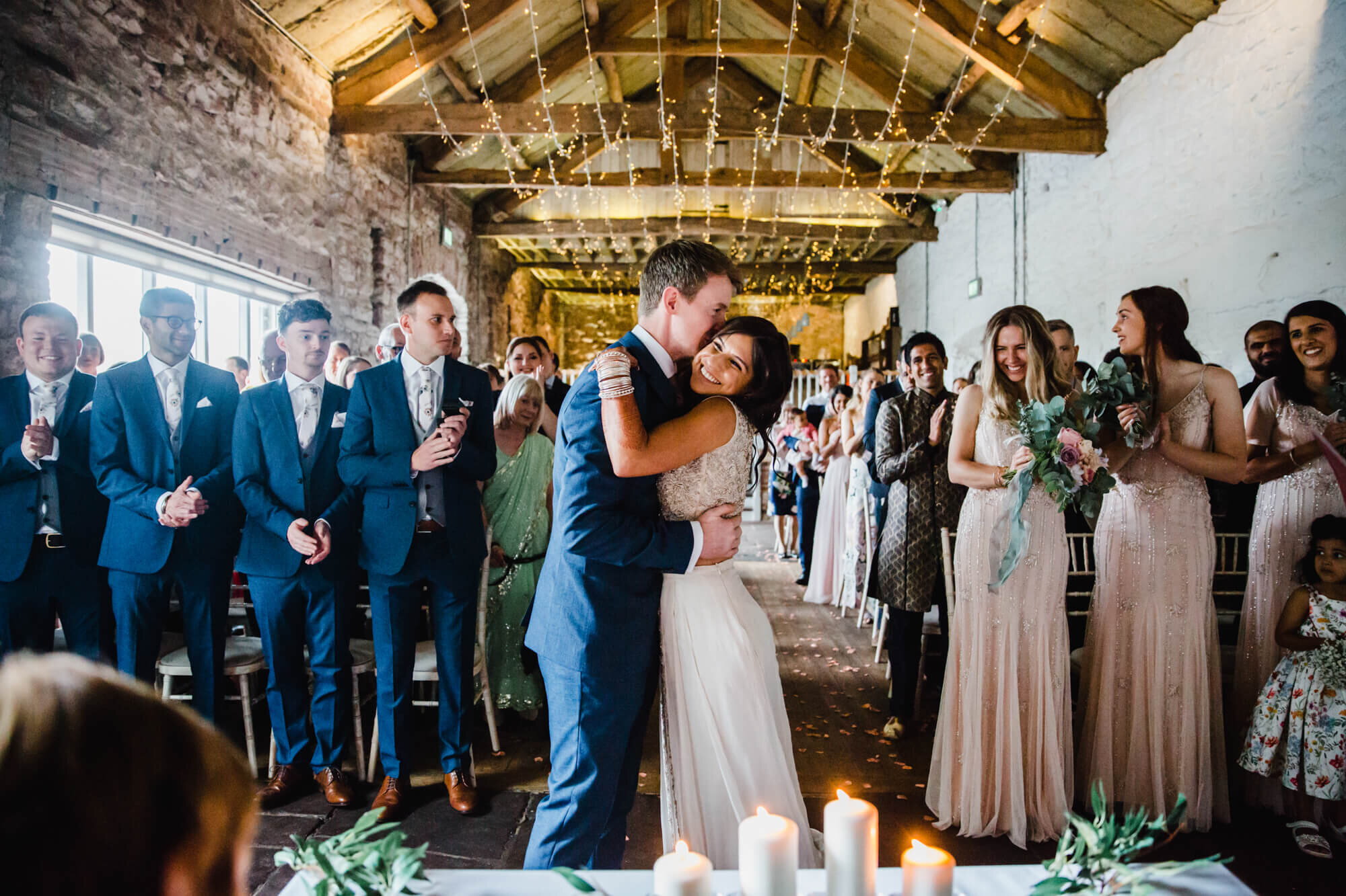 intimate moment as bride and groom share first kiss in hall barn ceremony 