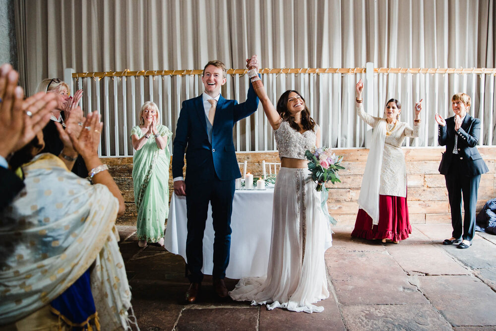 newlyweds celebrate by raising arms in air to celebrate marriage