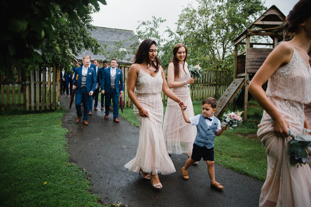 wedding guests follow bride and groom down path