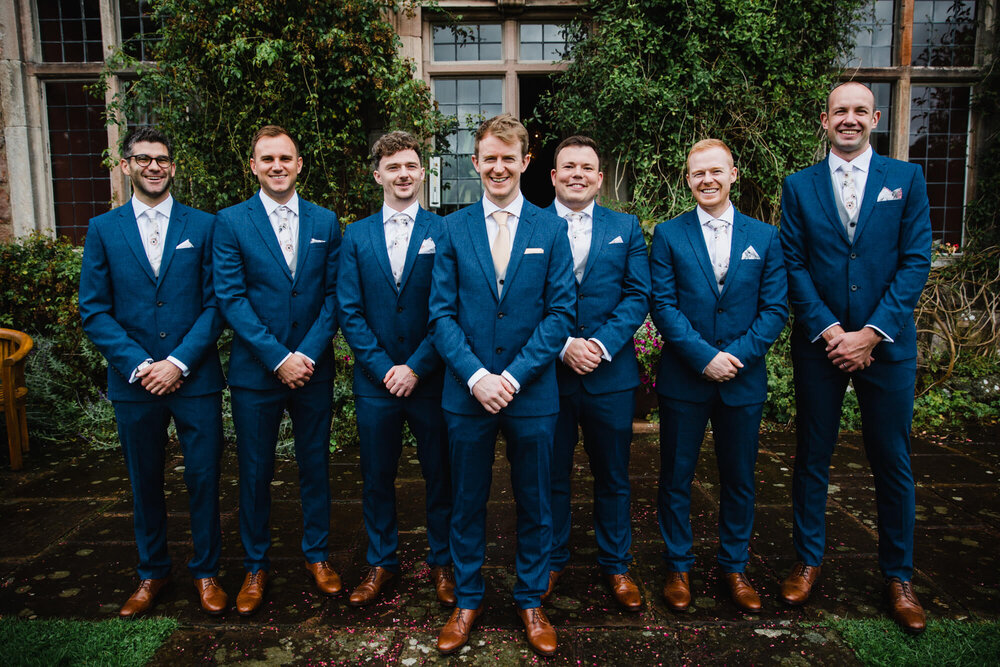 groomsmen pose for portrait in front of Askham Hall