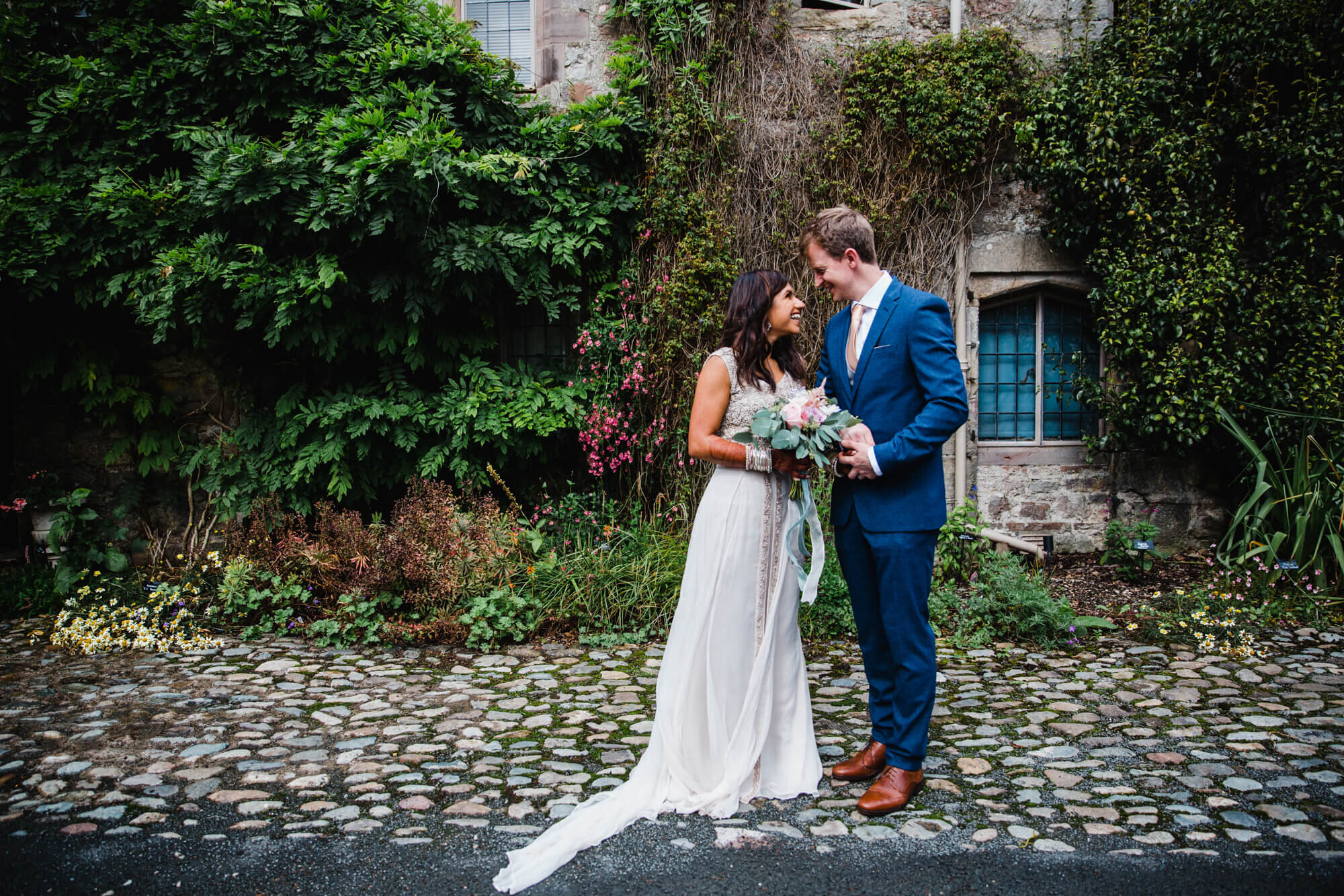 bride and groom pose together on cobbled courtyard