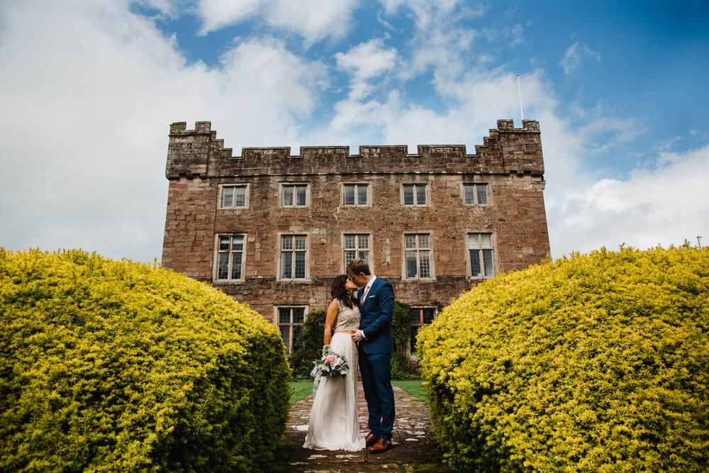 brochure style portrait as newlyweds pose in front of hall
