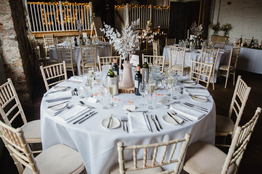 wide angle lens photograph of rustic wedding breakfast set up in barn