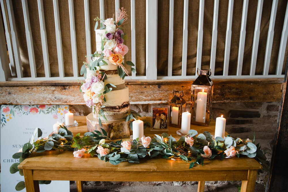wedding cake and gifts table by barn wall