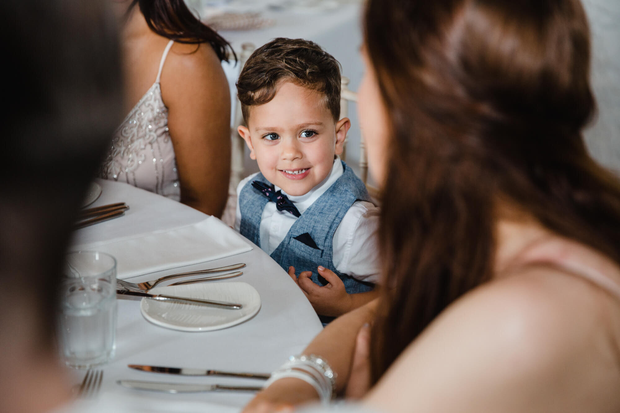 pageboy smiling at mum at wedding breakfast table