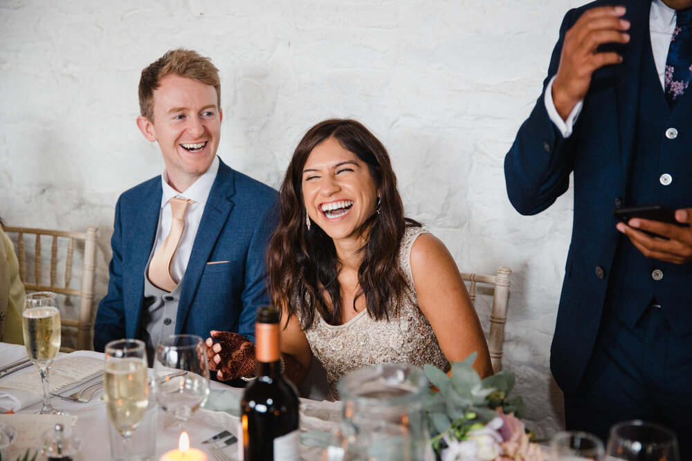 bride laughing at speeches told by best man