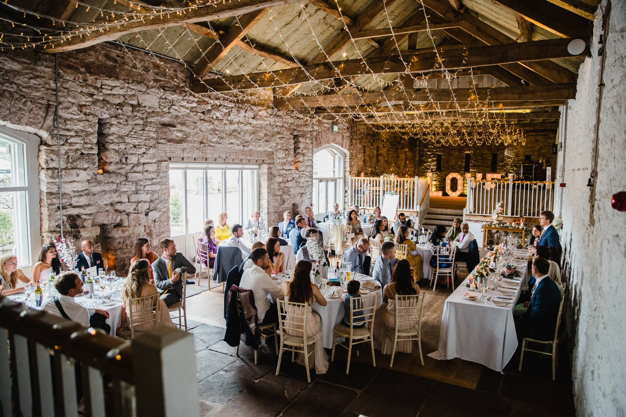 wide angle lens photograph of groom delivering speech to wedding party from gallery