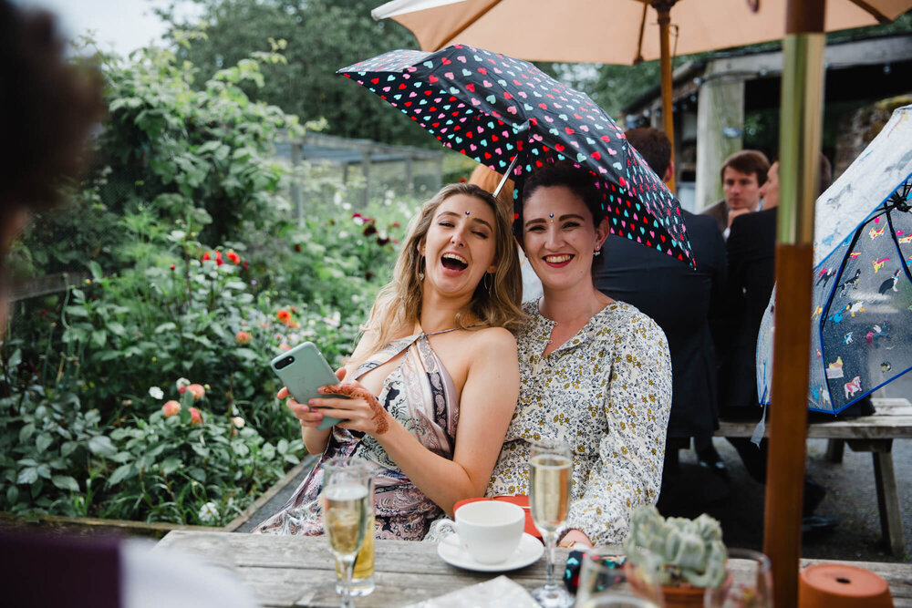 guests pose under umbrella while holding phone camera