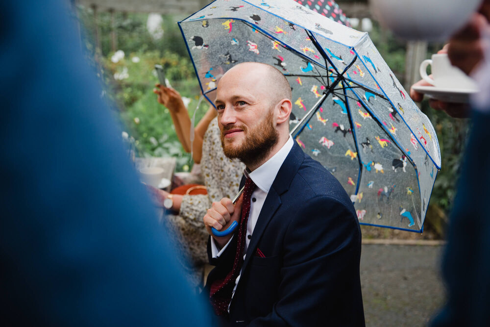 wedding guest under umbrella chatting to friends
