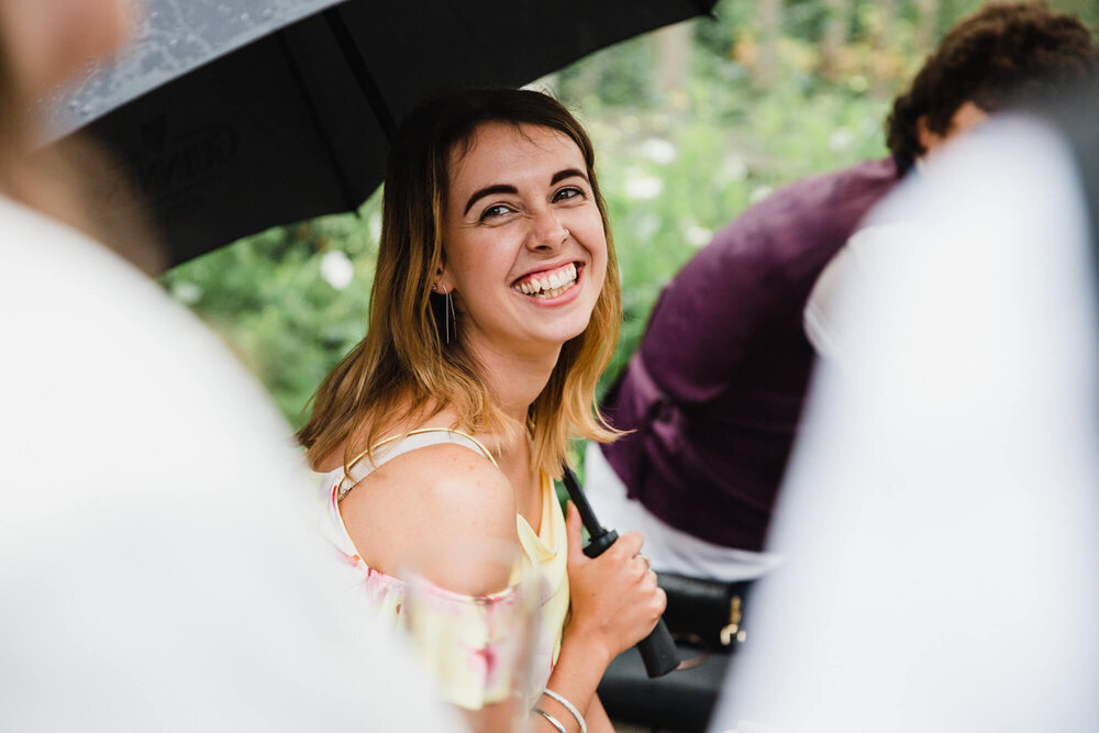 bridesmaid laughing under umbrella