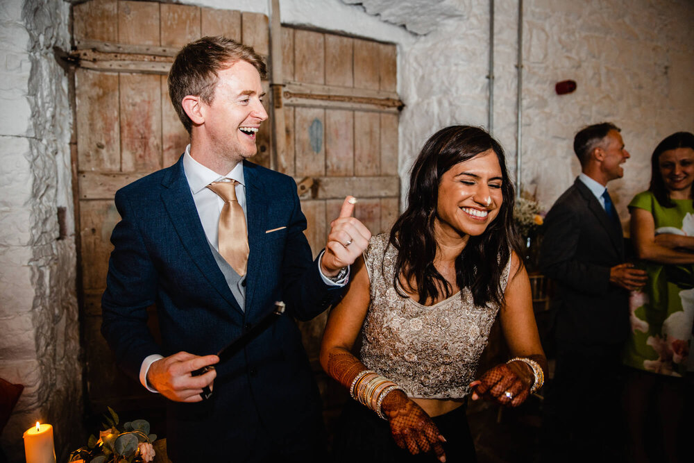 groom laughs as he tips icing onto nose of bride