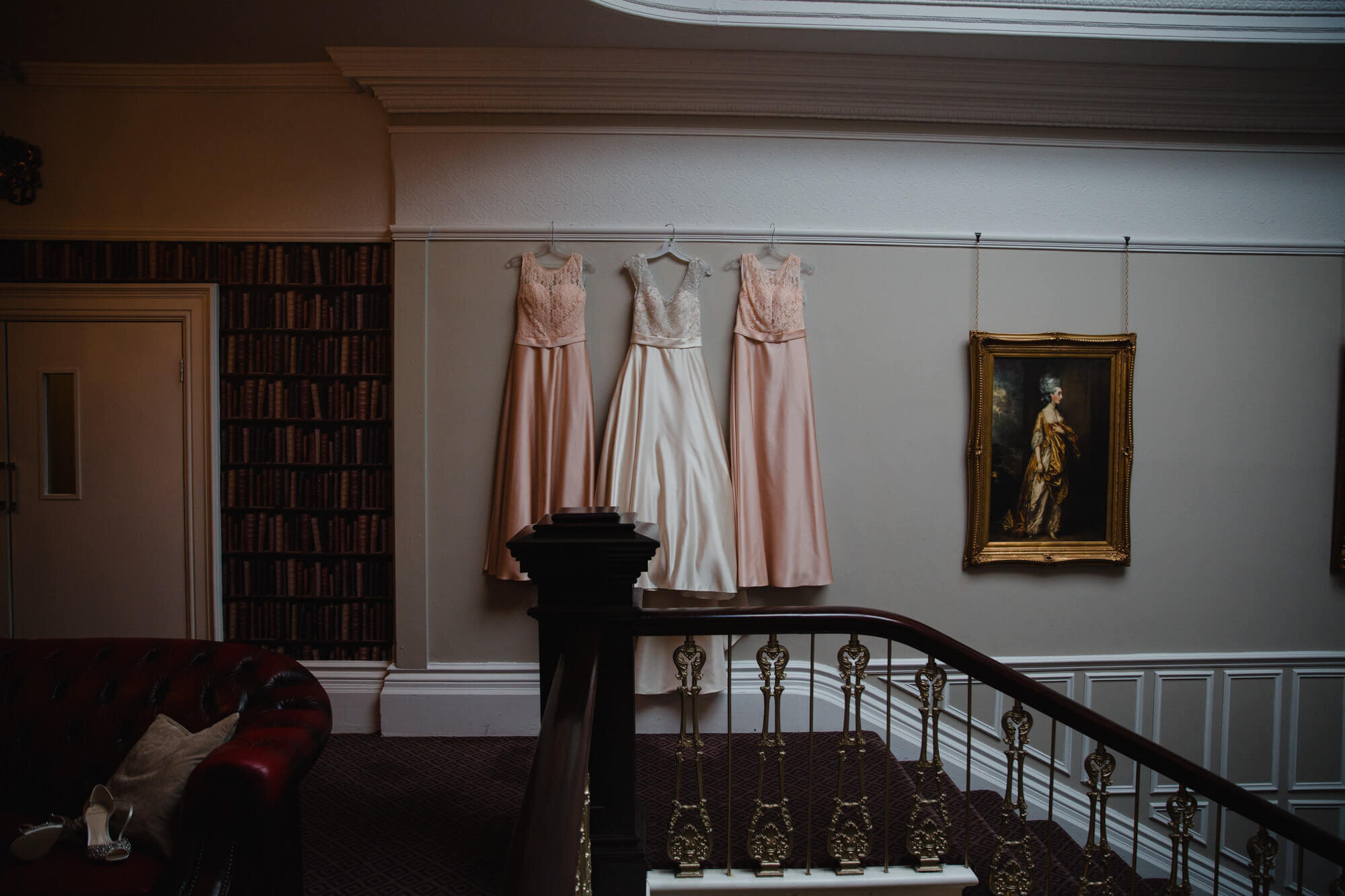 wedding dress alongside bridesmaid dresses on staircase at Ashfield House