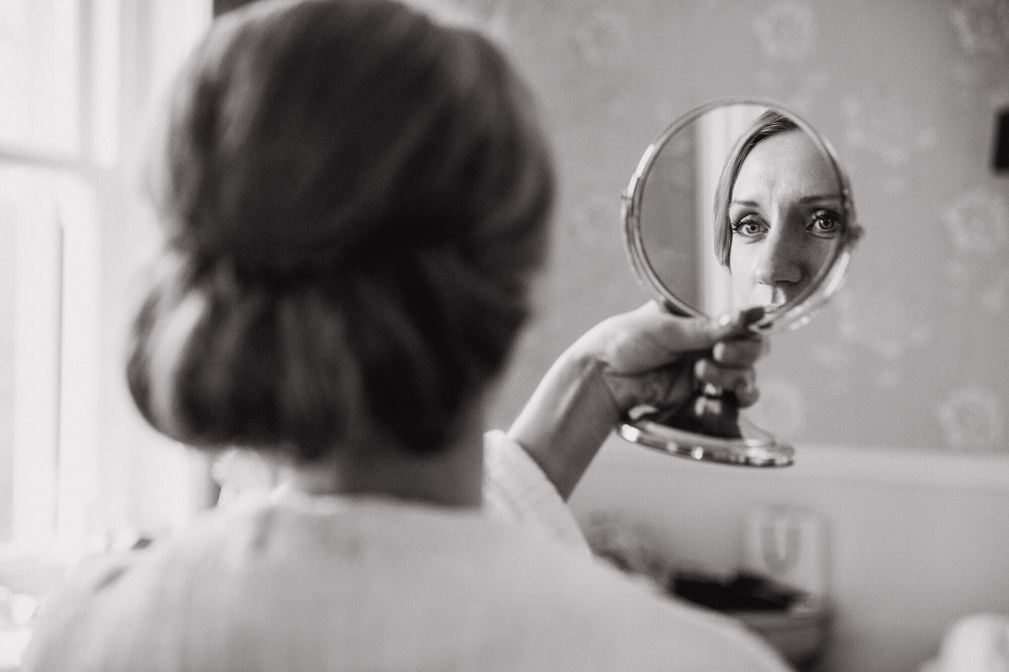 monochrome photograph of bride looking in mirror in bridal suite of Ashfield House