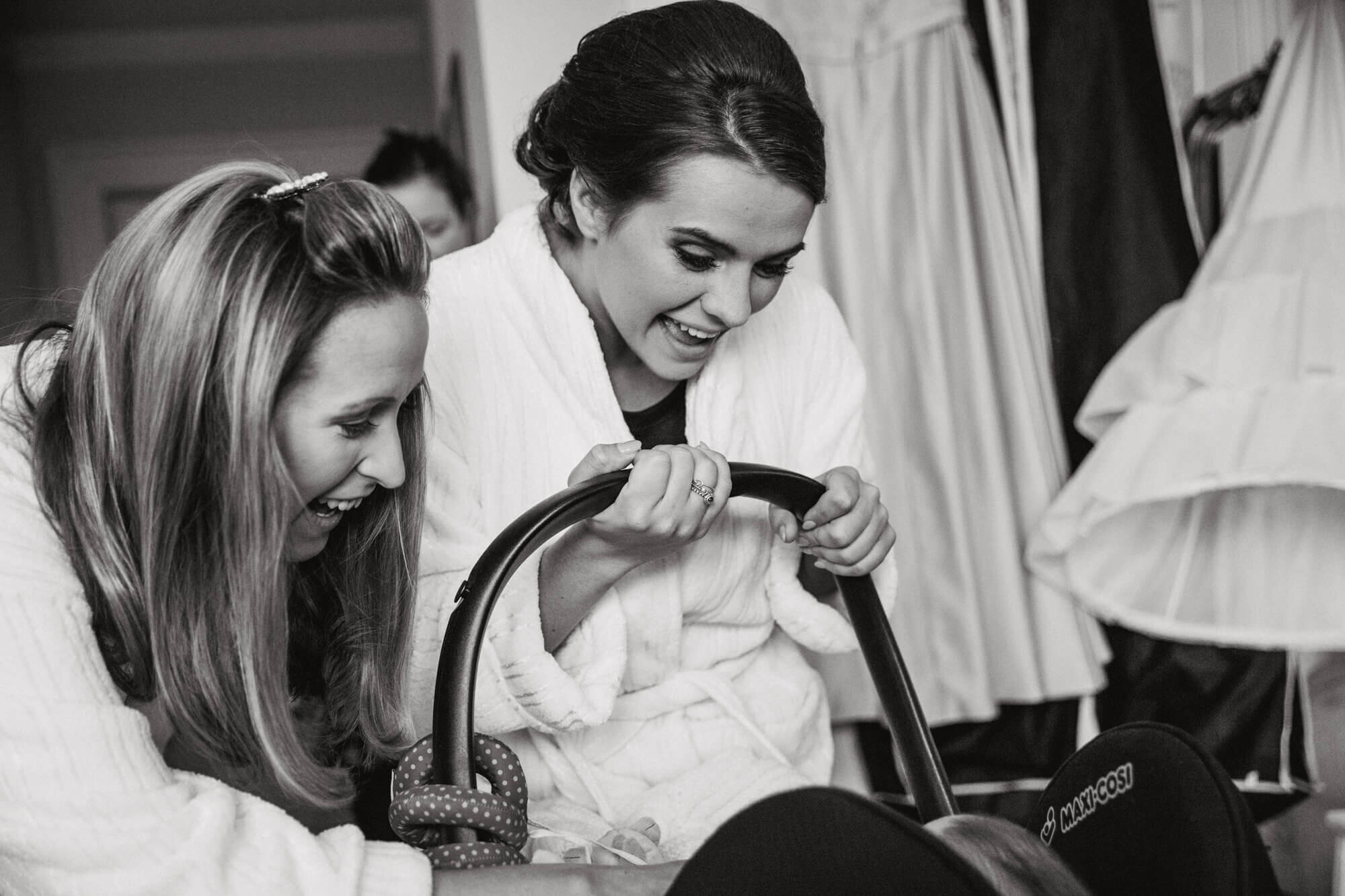 black and white photograph of bridesmaids laughing with baby