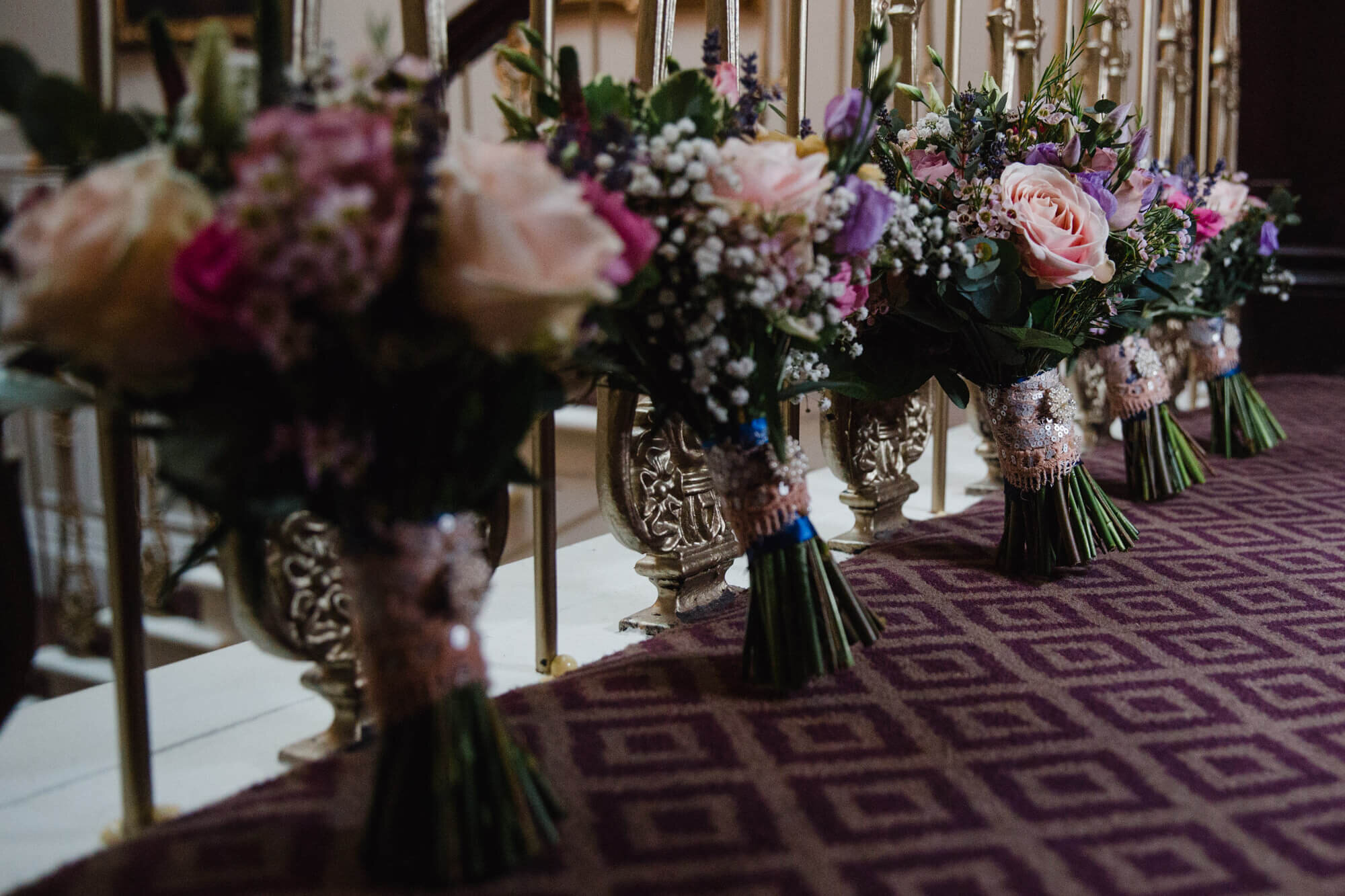 Floral bouquets lined up against bannister on staircase