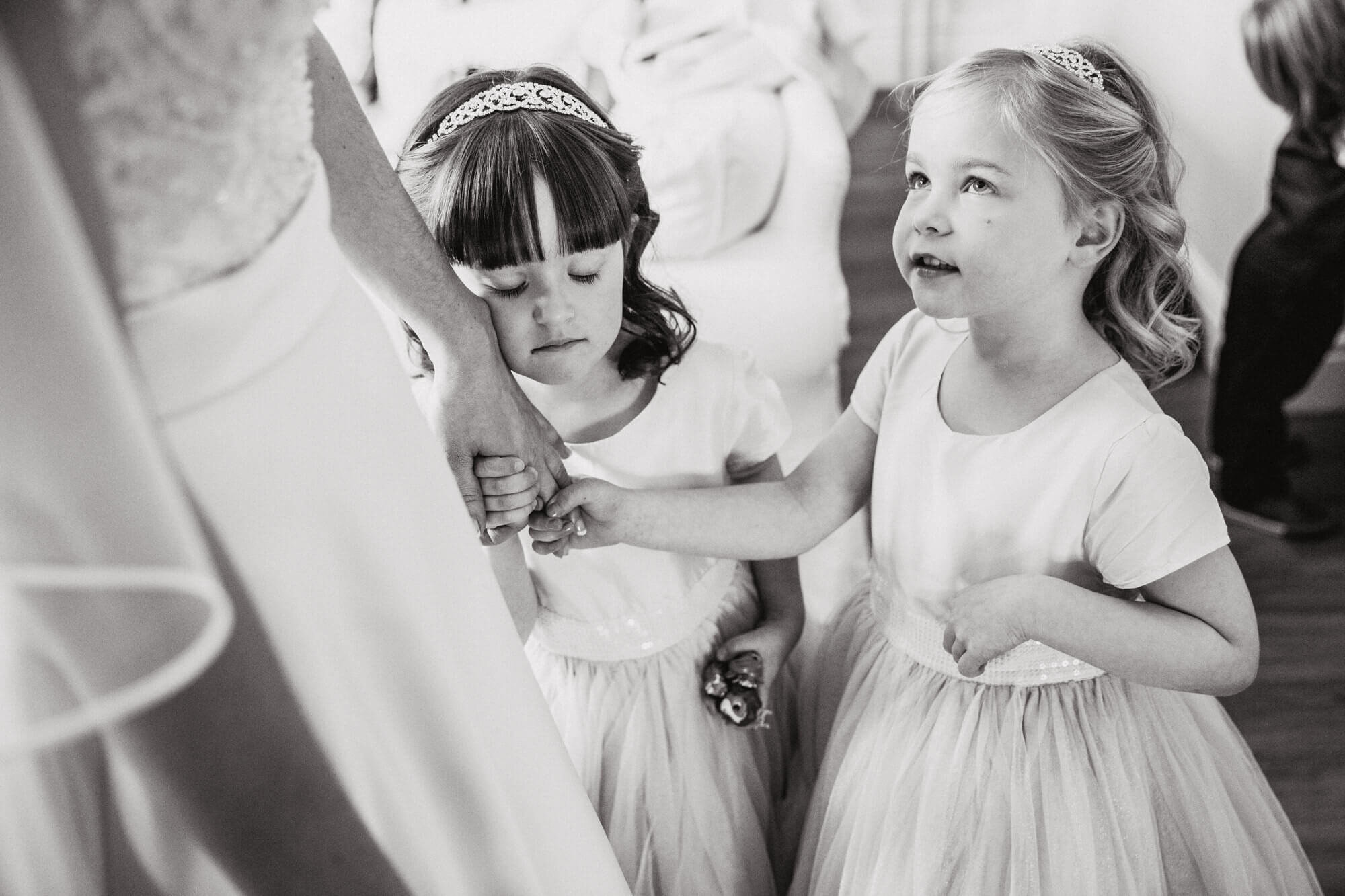 black and white moment of flower girls holding brides hand