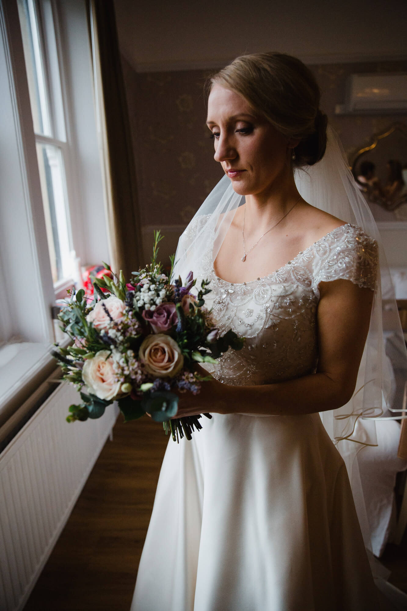 bride holding flower bouquet in window light