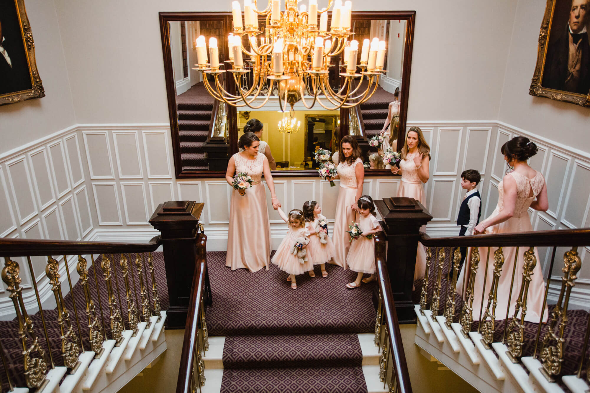 bridal party make their way down grand staircase at Ashfield House