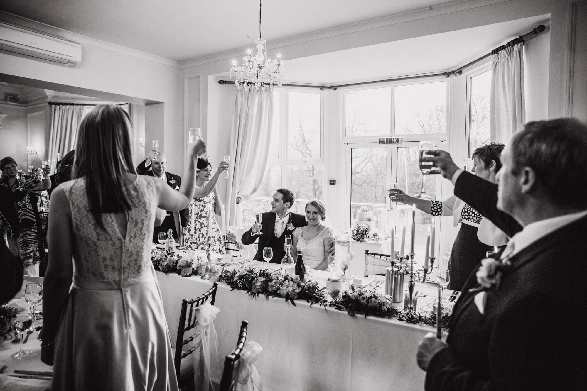 wedding party raising glasses to newly married couple on top table