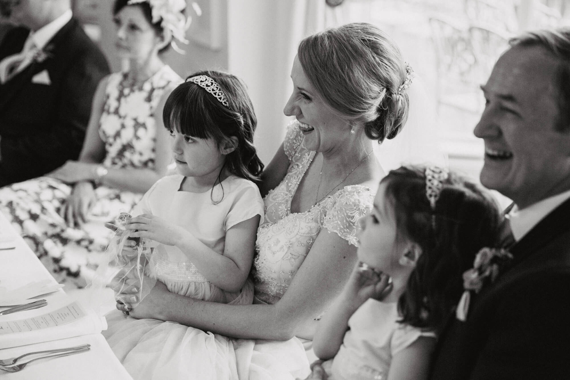 candid moment as flower girl sits on brides knee