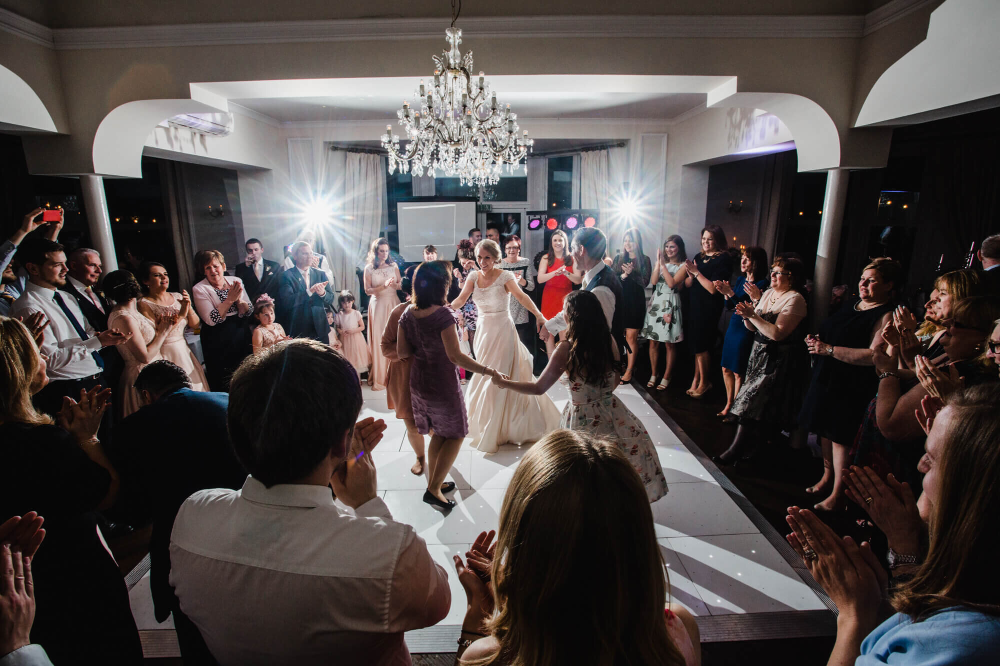 creative wedding photography as newlyweds dance surrounded by friends and family