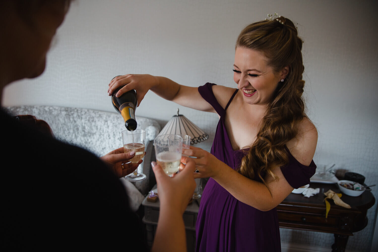 bridesmaid pouring champagne into flutes for bridal party