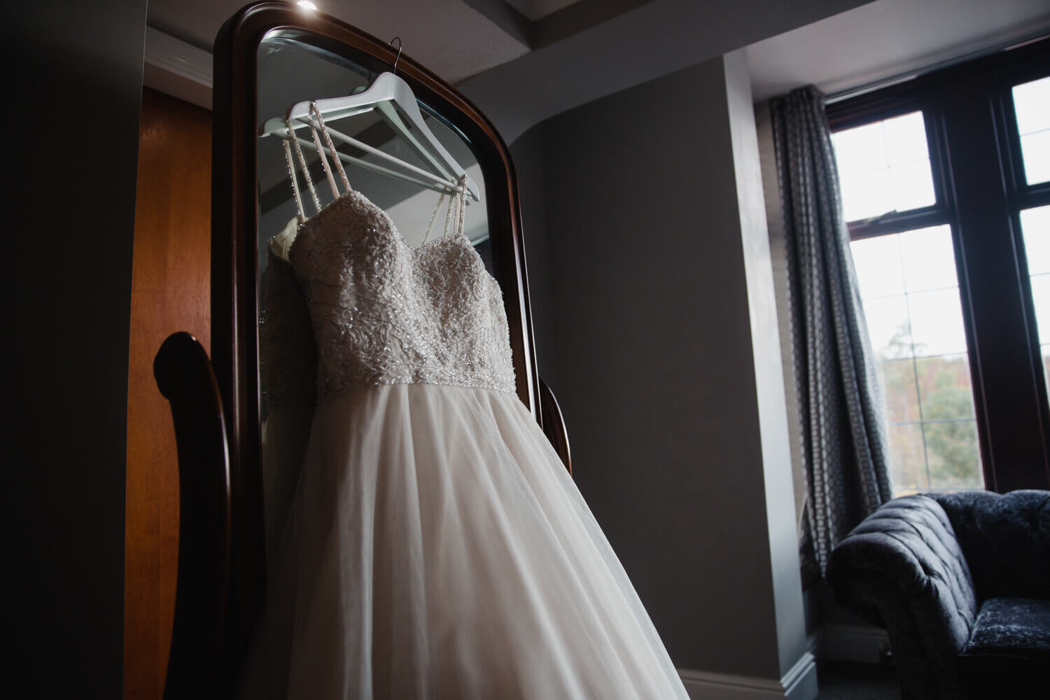 detailed photograph of wedding dress hanging on mirror in bridal suite