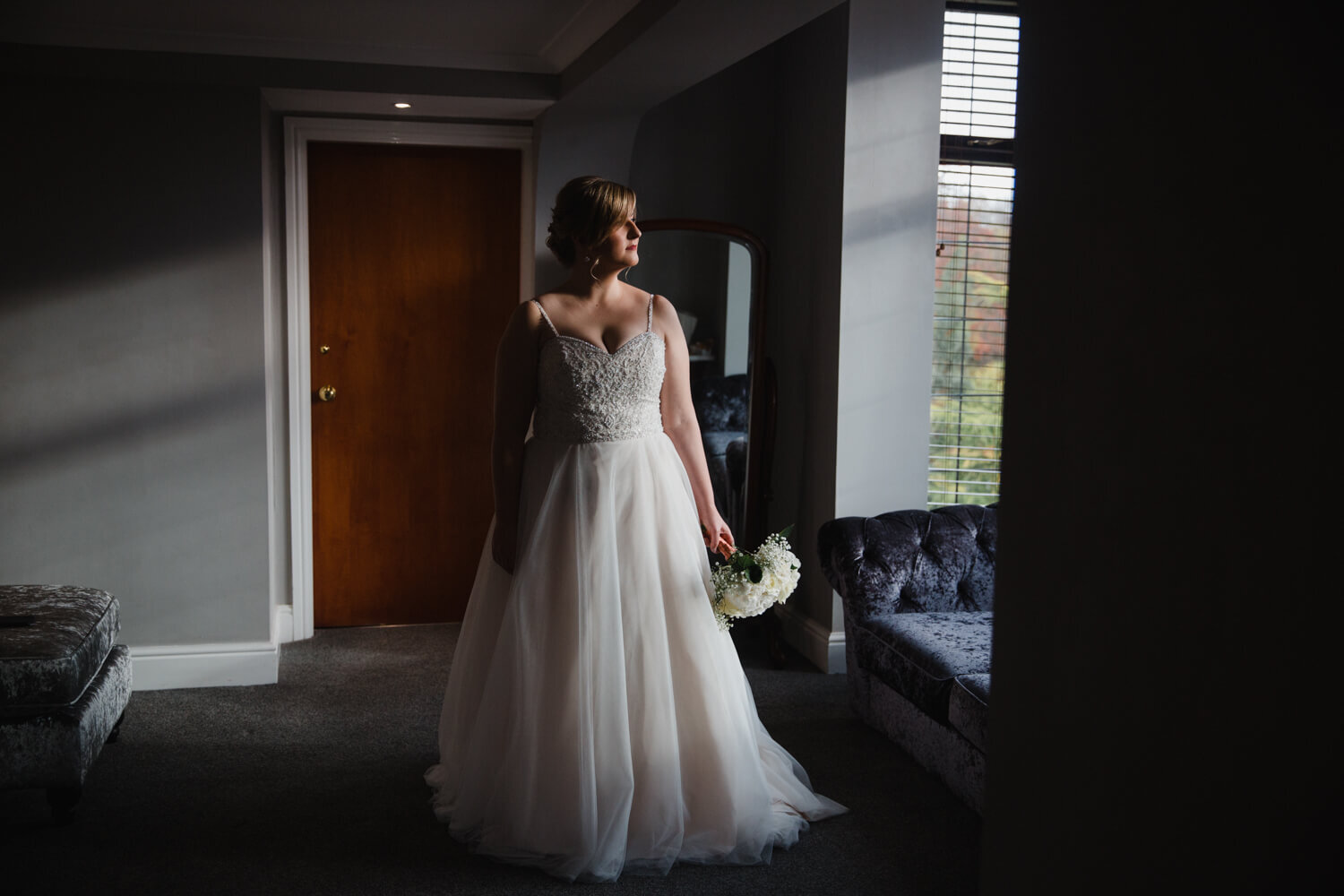 low exposure photograph of bride holding bouquet in window light of Oakwell Hall