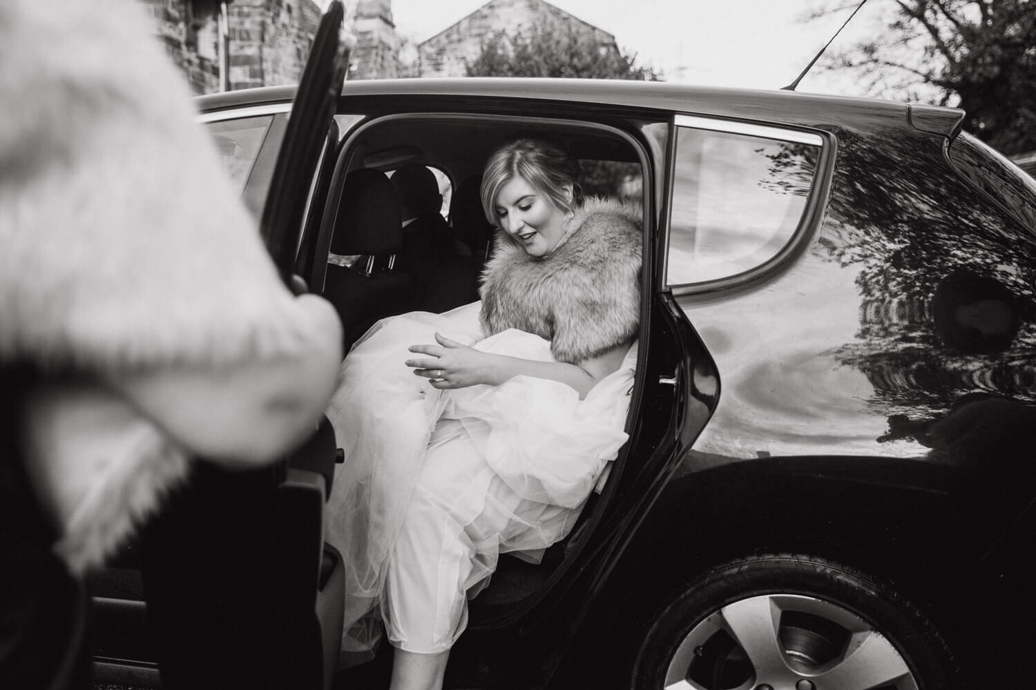 black and white photograph of bride arriving in wedding car