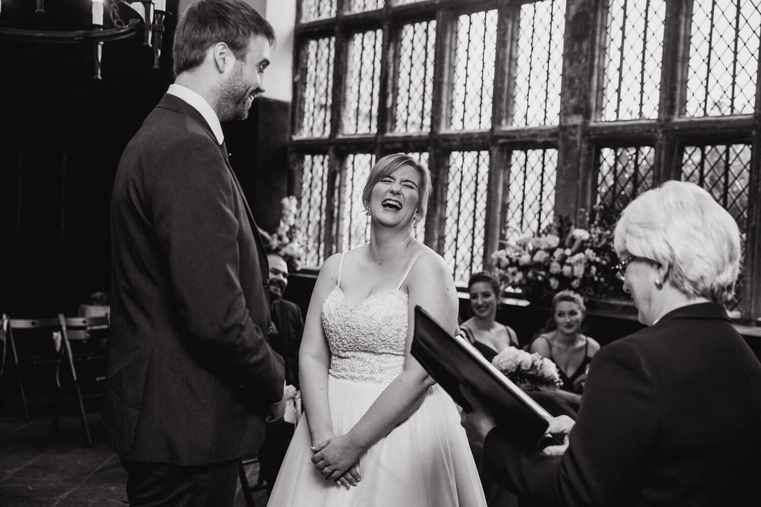 monochrome photograph of bride and groom laughing during service at Oakwell Hall