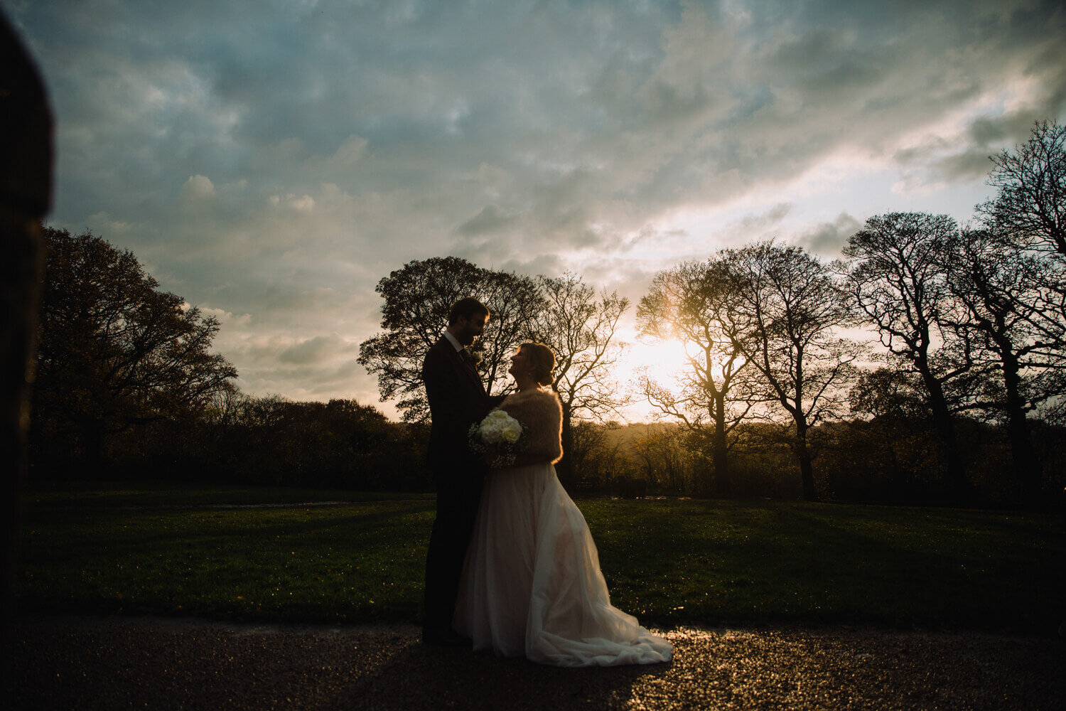 silhouette portrait of bride and groom posing with sunset backdrop