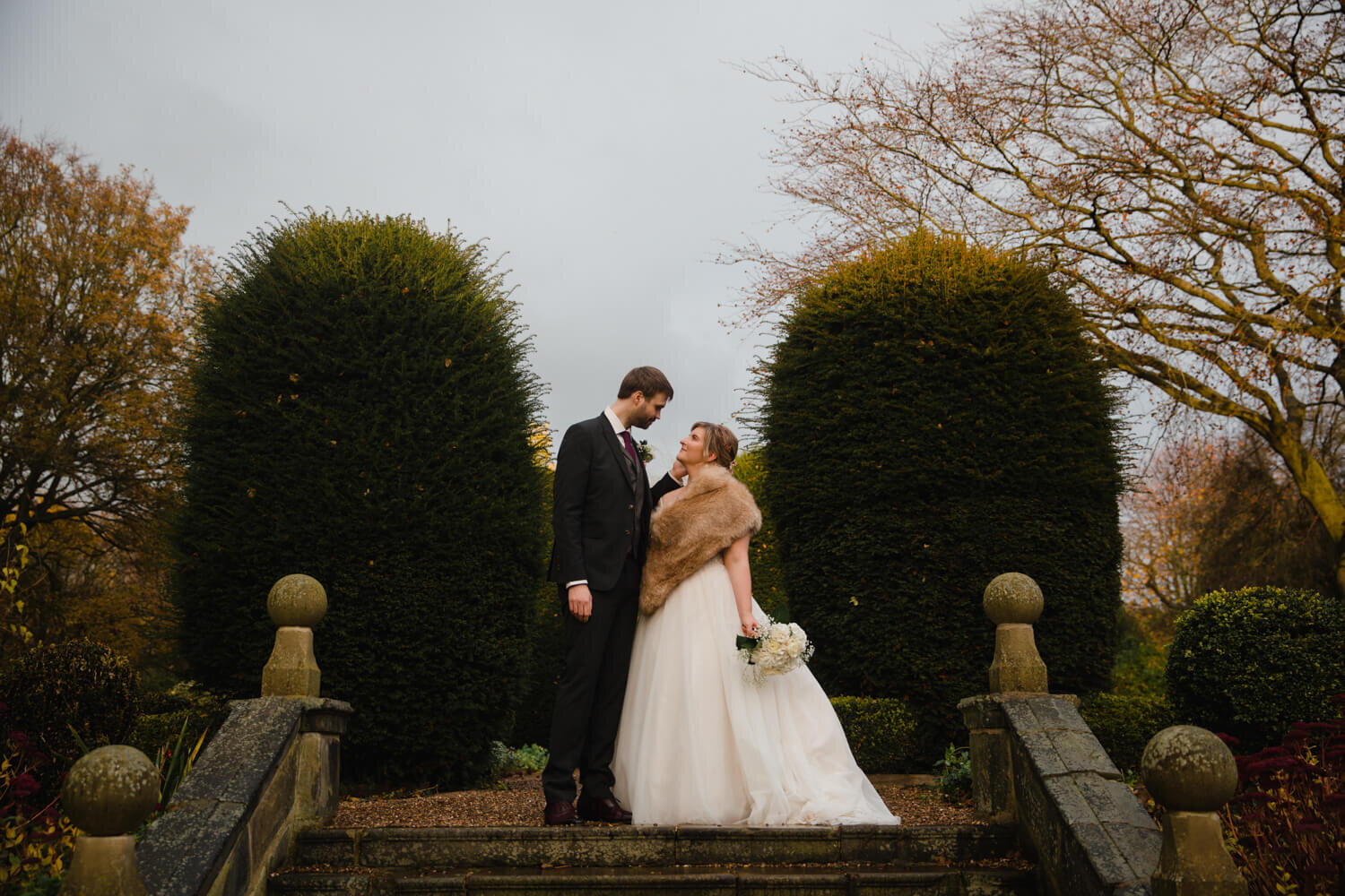 portrait on steps of bride and groom in Oakwell Hall gardens