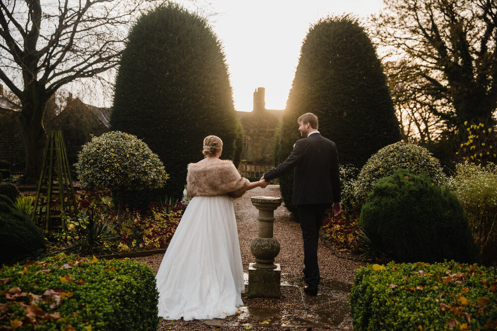 portrait with newly wedded couple holding hands in gardens
