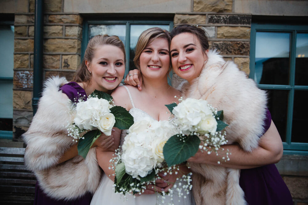 bride and bridesmaids holding bouquets while looking into camera