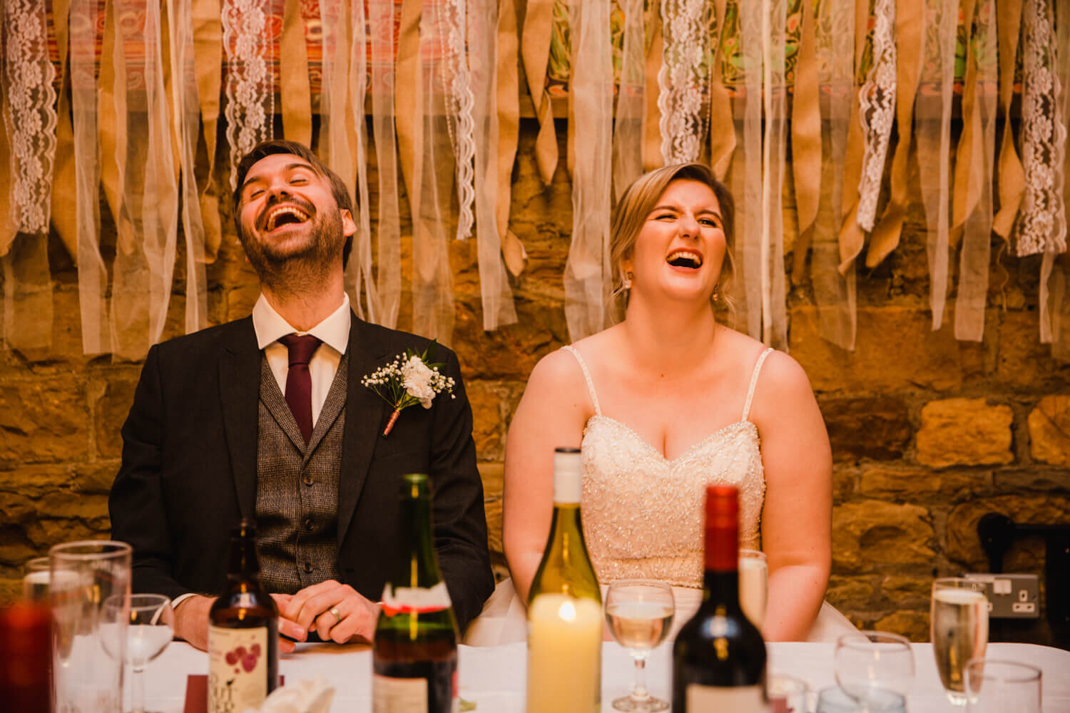 bride and groom laughing at speeches together