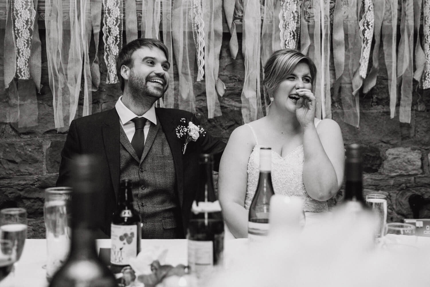 black and white monochrome photograph of wedded couple enjoying speeches