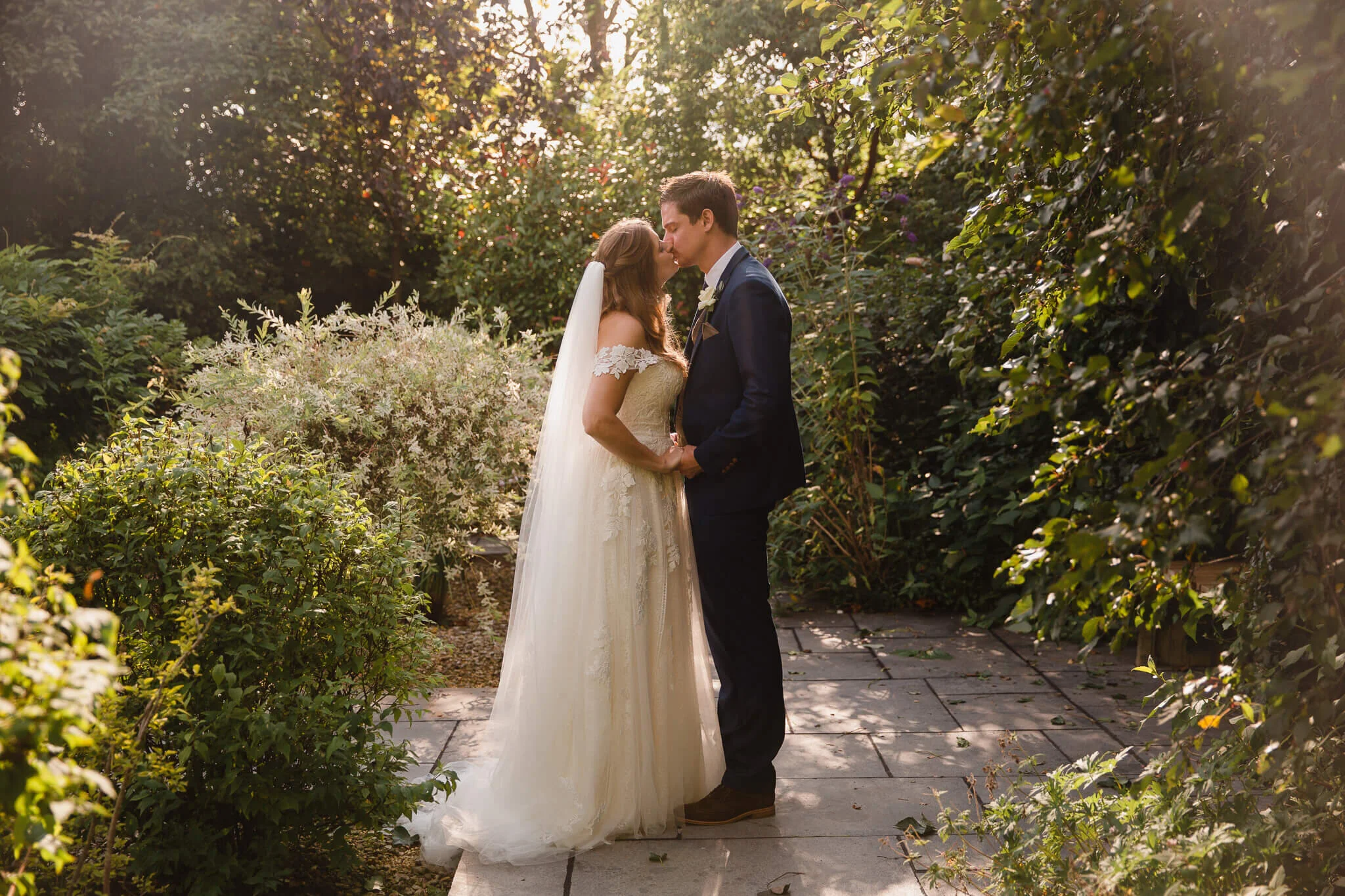 Kerry and James sharing a golden‑hour kiss at their Styal Lodge summer wedding.