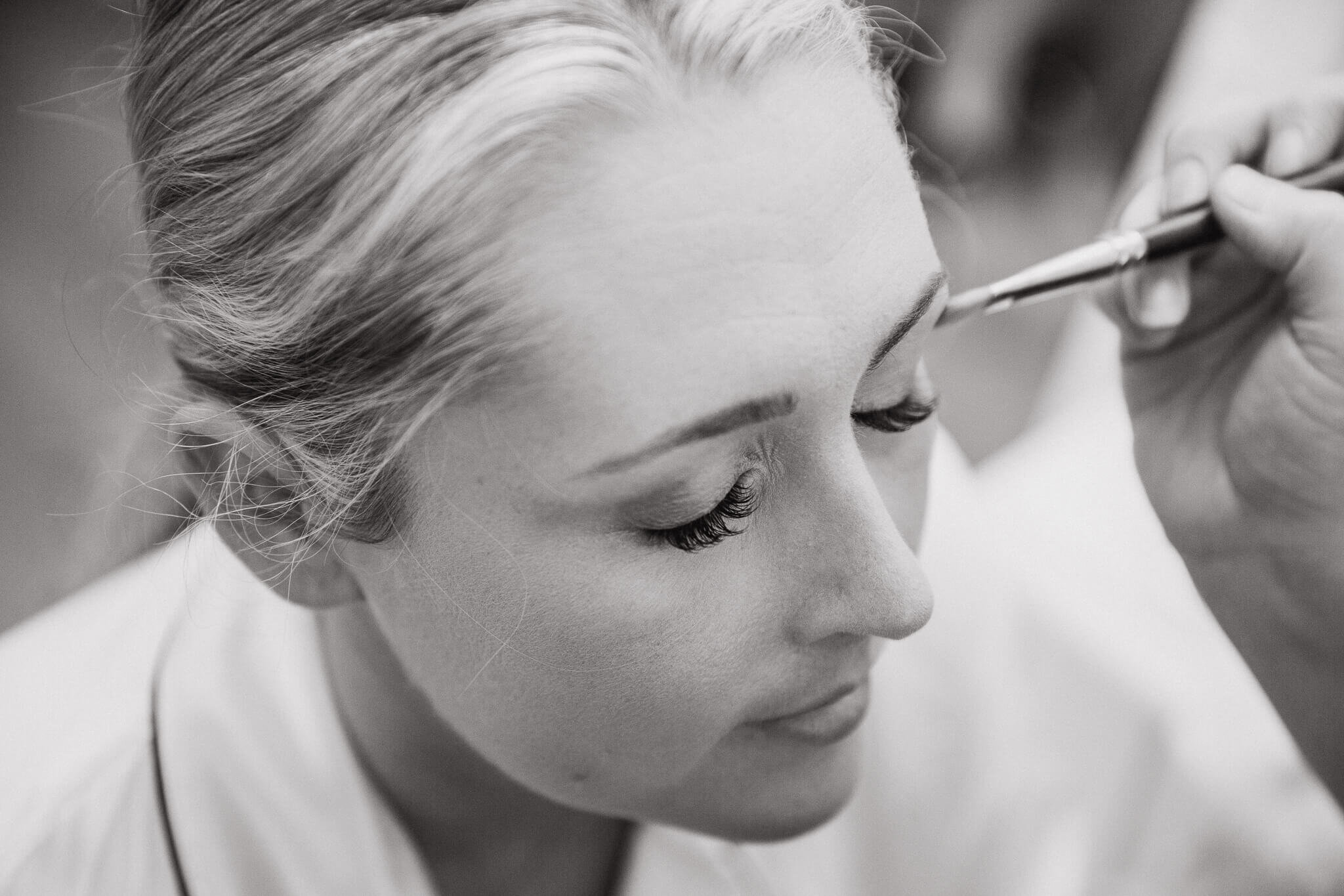 monochrome photograph of bride having make up done