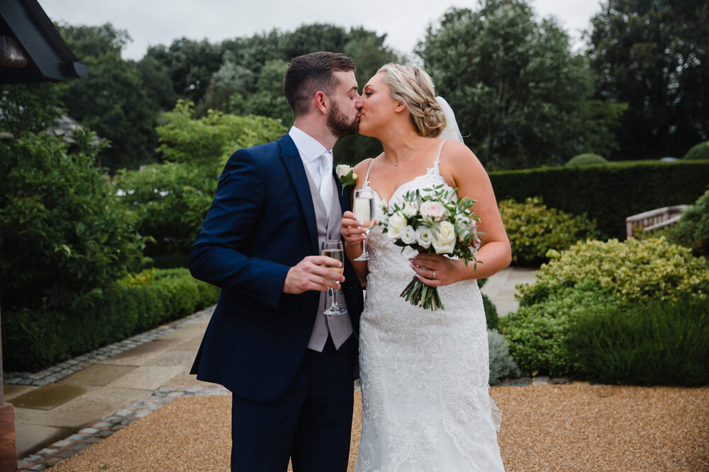 newlyweds share kiss in gardens of wedding lodge