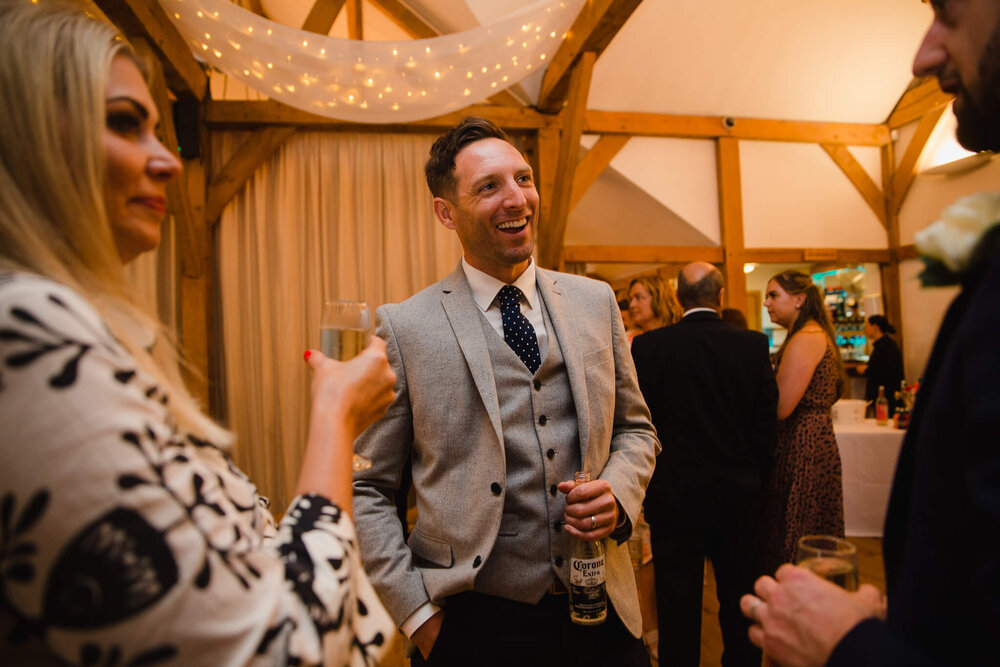 relaxed, unposed wedding guests share joke in reception venue