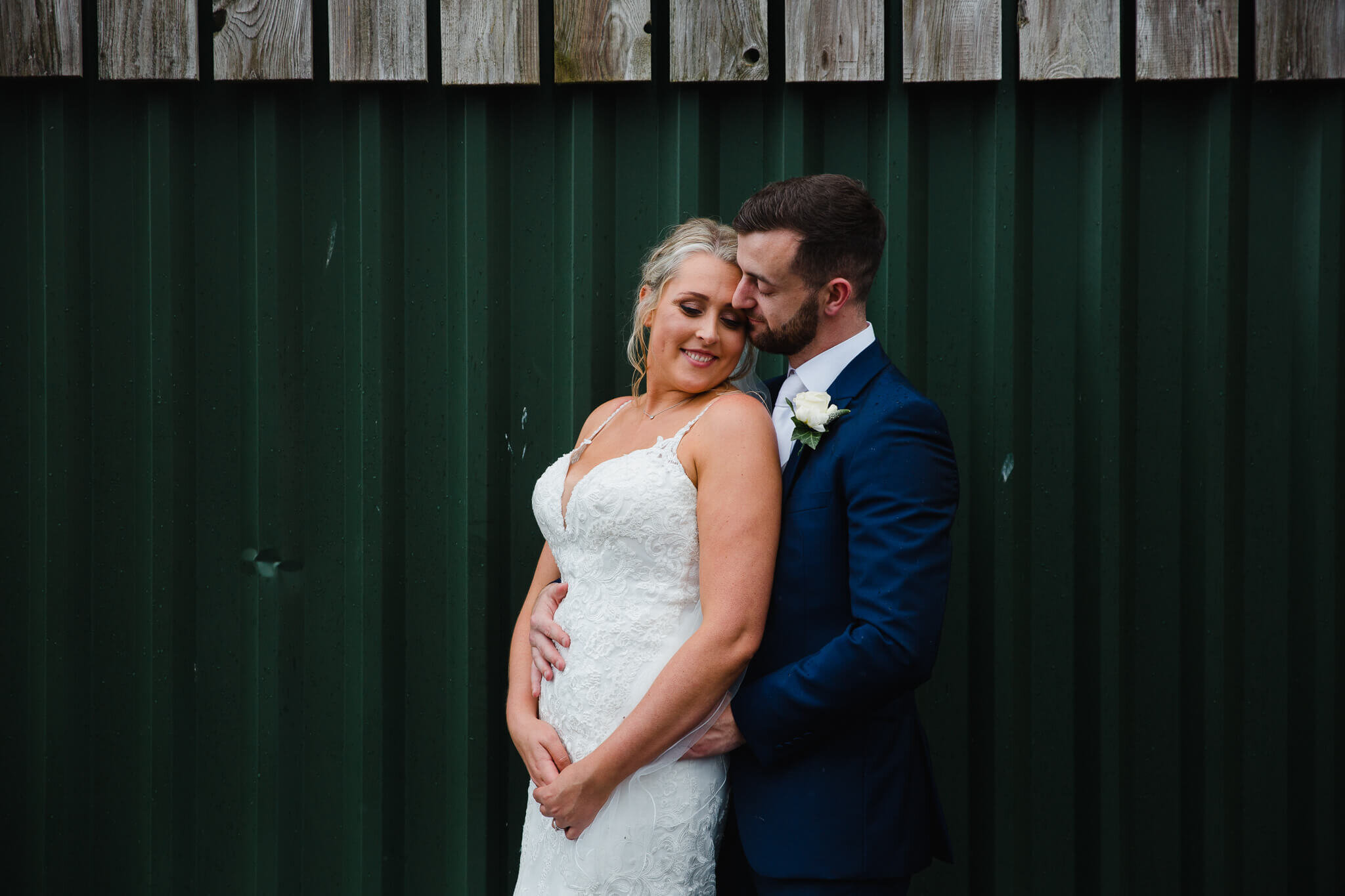 intimate relaxed portrait of bride and groom with shed backdrop