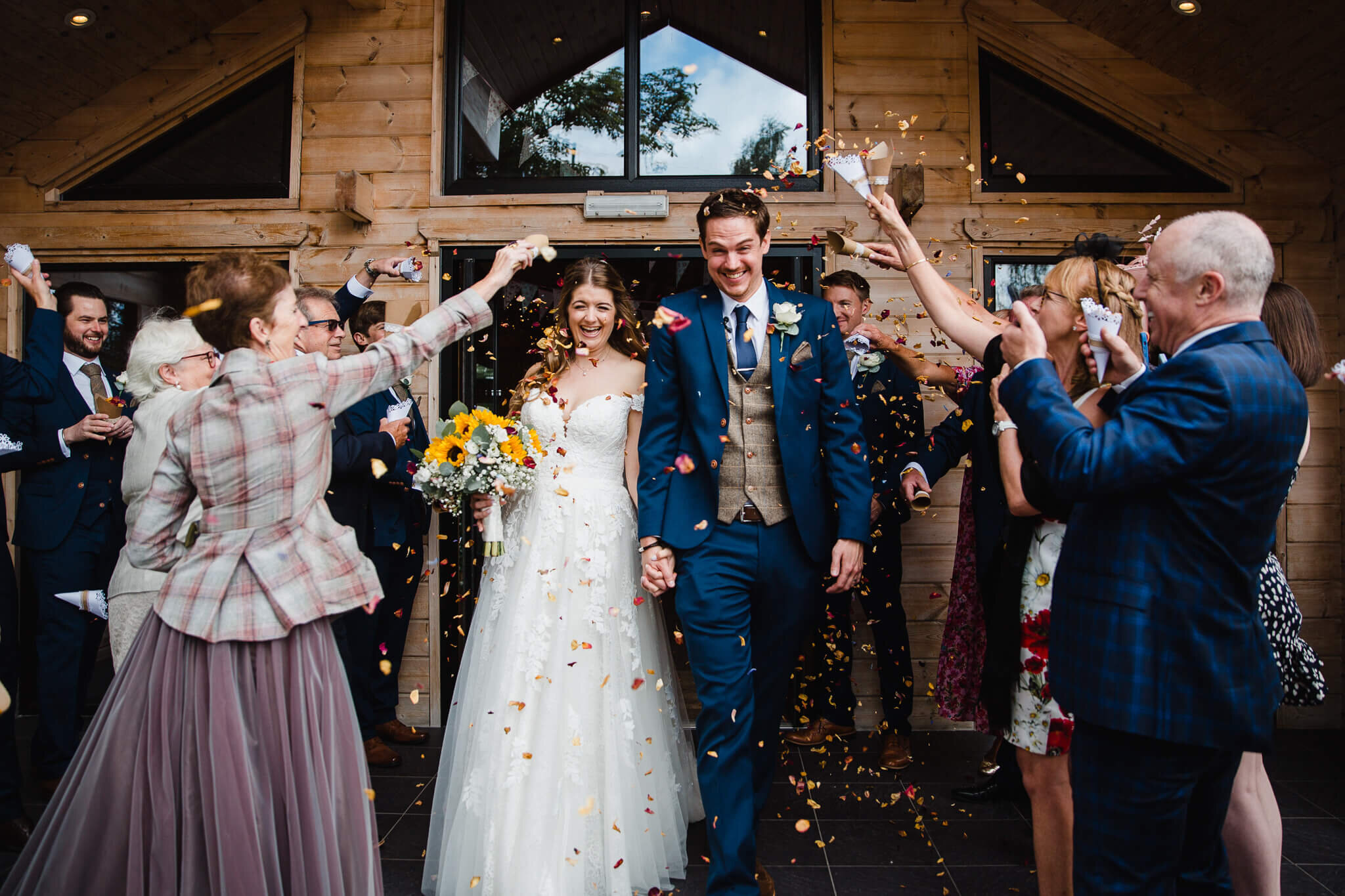 Newlyweds showered in autumnal coloured leaves after leaving the entrance