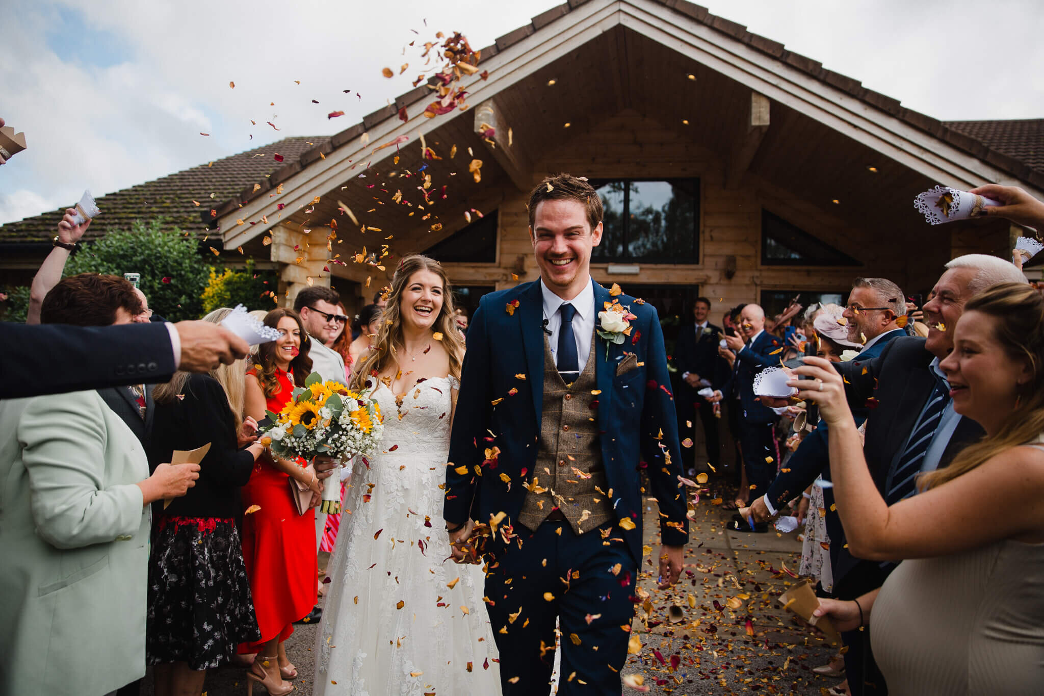 guests throw confetti over newly wedded couple