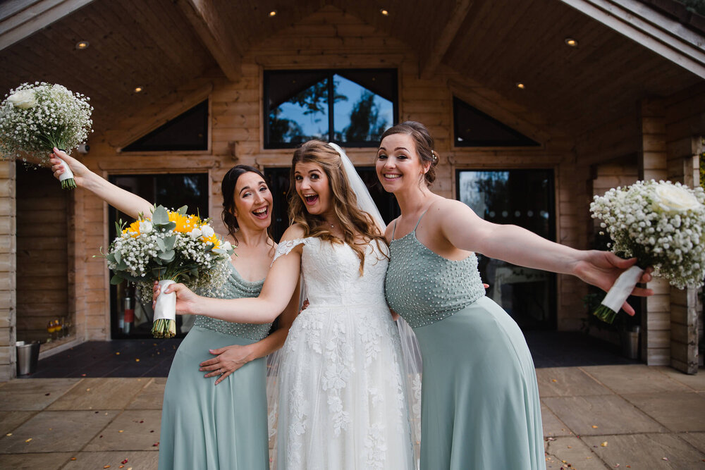 bride poses with bridesmaids outside entrance to styal lodge