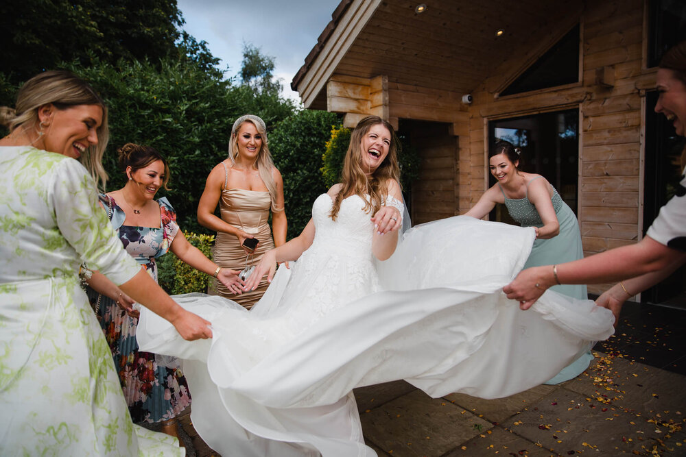 bridesmaids and guests playing with brides dress