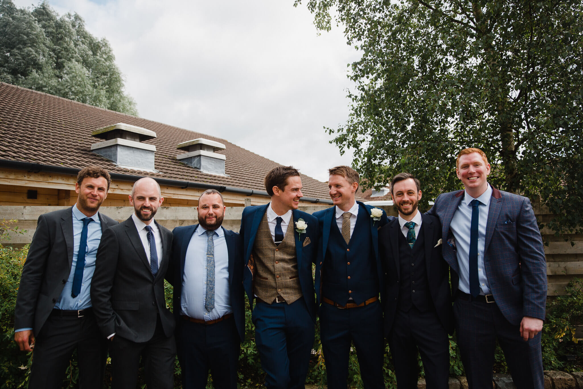 groomsmen line up for portrait together in grounds